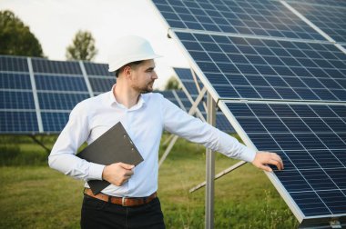 Güneş çiftliği, mühendis ile güneş paneli sistemin işleyişini kontrol eder, dünyanın enerjisini korumak için alternatif enerji, temiz enerji üretimi için fotovoltaik modül fikri.