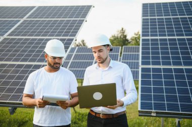 Güneş panellerinin arka planında iki mühendis ya da işadamı. Yenilenebilir enerji. Yeşil enerji.