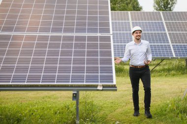 Young architect standing by solar panels.