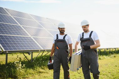 Güneş panelleri enerji çiftliğinde çalışan mühendis. Güneş enerjisi istasyonunda çalışan iki teknisyen..