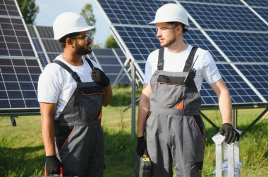 Güneş panelleri enerji çiftliğinde çalışan mühendis. Güneş enerjisi istasyonunda çalışan iki teknisyen..