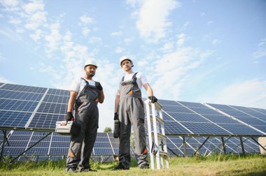 Güneş enerjisi santralinde kontrol ve bakım üzerinde çalışan mühendislik ekibi güneş paneli teknisyenleri güneşli bir günde.