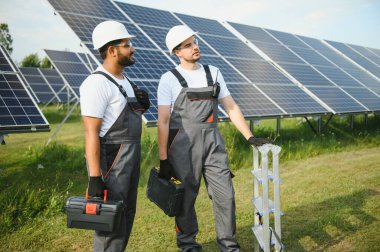 Güneş panelleri enerji çiftliğinde çalışan mühendis. Güneş enerjisi istasyonunda çalışan iki teknisyen..