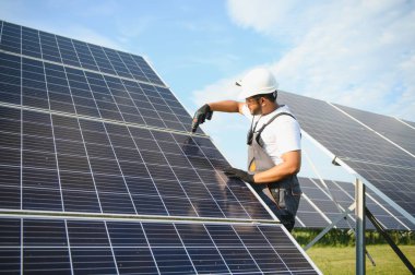Tornavidalı Hintli işçi güneş panelleri üzerinde çalışıyor. Yenilenebilir enerji.