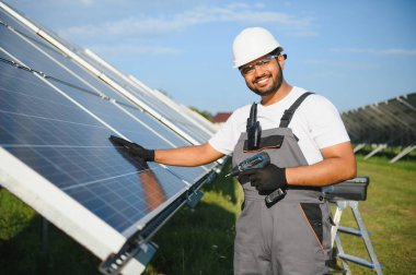 Tornavidalı Hintli işçi güneş panelleri üzerinde çalışıyor. Yenilenebilir enerji.