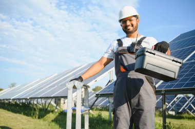 Güneş panelleri yakınındaki yakışıklı Hintli işçinin portresi.
