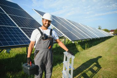 Güneş çiftliğinde üniformalı bir Hintli. Yetkin enerji mühendisi fotovoltaik hücrelerin çalışmalarını kontrol ediyor.