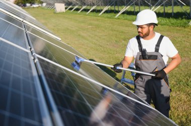 Profesyonel Hintli işçi güneş panellerini fırça ve yeşil elektrik teknolojisiyle temizliyor..