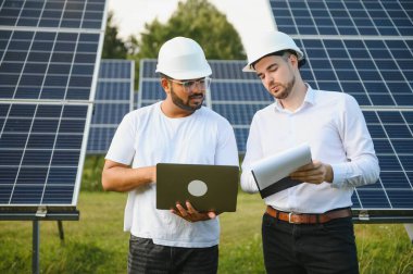 Güneş çiftliği, güneş paneli ve iki mühendis sistemin işleyişini kontrol etmek için yürür, dünyanın enerjisini korumak için alternatif enerji, temiz enerji üretimi için fotovoltaik modül fikri