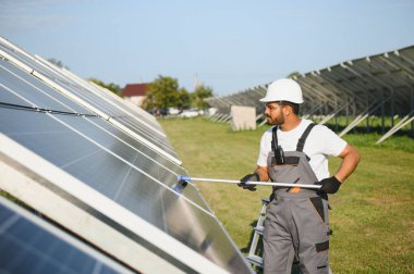 Genç bir Hintli temizlikçi güneş panellerini temizliyor..