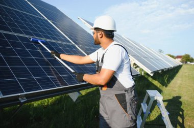 Profesyonel Hintli işçi güneş panellerini fırça ve yeşil elektrik teknolojisiyle temizliyor..
