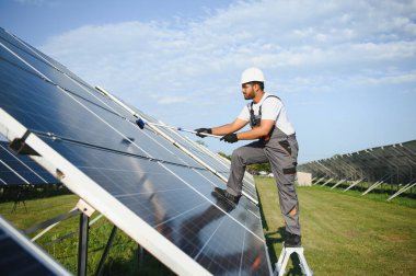 Profesyonel Hintli işçi güneş panellerini fırça ve yeşil elektrik teknolojisiyle temizliyor..