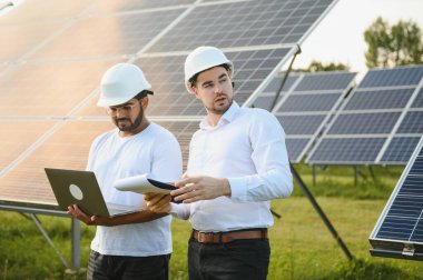 Güneş panellerinin arka planında iki mühendis ya da işadamı. Yenilenebilir enerji. Yeşil enerji.