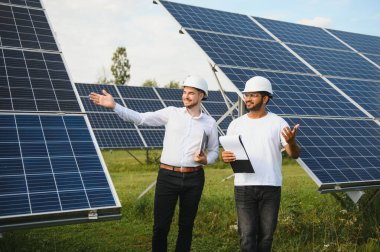 İki mühendis açık güneş fotovoltaik paneller incelemesini yapıyorlar.
