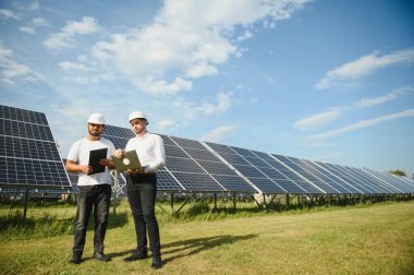 Güneş çiftliği, güneş paneli ve iki mühendis sistemin işleyişini kontrol etmek için yürür, dünyanın enerjisini korumak için alternatif enerji, temiz enerji üretimi için fotovoltaik modül fikri
