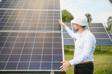 Güneş çiftliği, mühendis ile güneş paneli sistemin işleyişini kontrol eder, dünyanın enerjisini korumak için alternatif enerji, temiz enerji üretimi için fotovoltaik modül fikri.