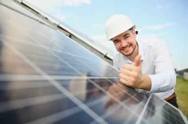 Young architect standing by solar panels.