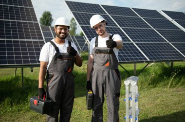 Güneş panelleri enerji çiftliğinde çalışan mühendis. Güneş enerjisi istasyonunda çalışan iki teknisyen..