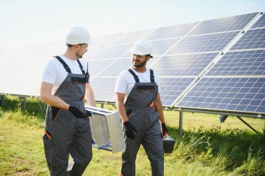 İki mühendisden oluşan bir ekip bir güneş enerjisi istasyonuna güneş panelleri kurmaya çalışıyor. Mühendis ekibi güneş pilleri kurma işini tartışıyor.