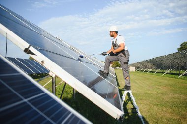 Profesyonel Hintli işçi güneş panellerini fırça ve yeşil elektrik teknolojisiyle temizliyor..