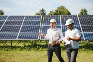 Güneş çiftliği, güneş paneli ve iki mühendis sistemin işleyişini kontrol etmek için yürür, dünyanın enerjisini korumak için alternatif enerji, temiz enerji üretimi için fotovoltaik modül fikri