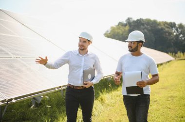 Güneş panellerinin arka planında iki mühendis ya da işadamı. Yenilenebilir enerji. Yeşil enerji.
