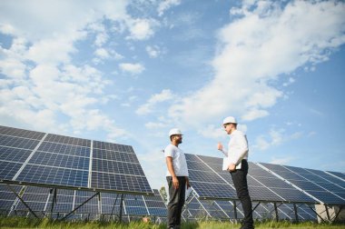 İki mühendis açık güneş fotovoltaik paneller incelemesini yapıyorlar.