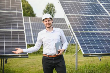 Güneş çiftliği, mühendis ile güneş paneli sistemin işleyişini kontrol eder, dünyanın enerjisini korumak için alternatif enerji, temiz enerji üretimi için fotovoltaik modül fikri.