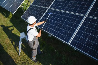 Profesyonel Hintli işçi güneş panellerini fırça ve yeşil elektrik teknolojisiyle temizliyor..