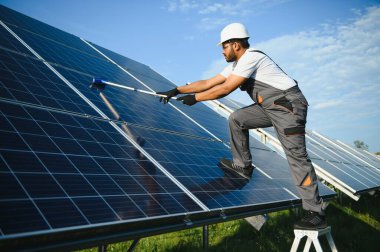 Profesyonel Hintli işçi güneş panellerini fırça ve yeşil elektrik teknolojisiyle temizliyor..