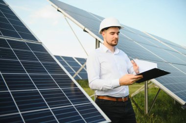 Young architect standing by solar panels.