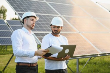 Güneş çiftliği, güneş paneli ve iki mühendis sistemin işleyişini kontrol etmek için yürür, dünyanın enerjisini korumak için alternatif enerji, temiz enerji üretimi için fotovoltaik modül fikri