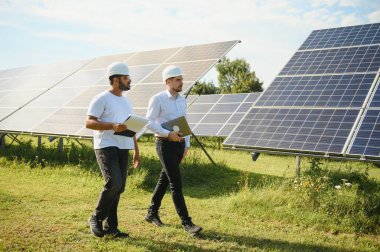 Güneş çiftliği, güneş paneli ve iki mühendis sistemin işleyişini kontrol etmek için yürür, dünyanın enerjisini korumak için alternatif enerji, temiz enerji üretimi için fotovoltaik modül fikri