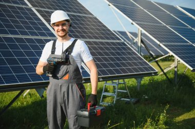 Fotovoltaik güneş modülleri monte eden adam teknisyen. Miğferdeki mühendis dışarıda güneş paneli kuruyor..