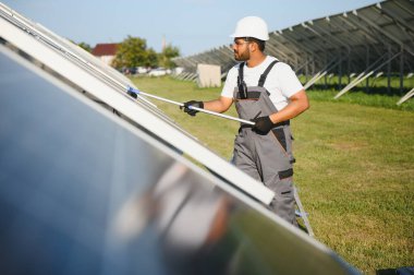 Profesyonel Hintli işçi güneş panellerini fırça ve yeşil elektrik teknolojisiyle temizliyor..
