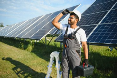 Güneş panelleri yakınındaki yakışıklı Hintli işçinin portresi.