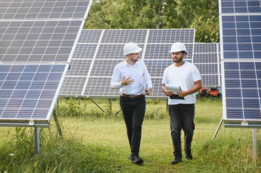 İki mühendis açık güneş fotovoltaik paneller incelemesini yapıyorlar.