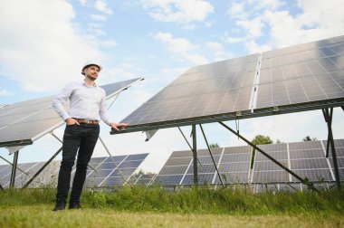Young architect standing by solar panels.
