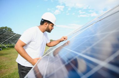 Erkek Arap mühendis güneş panelleri sıraları ile sahada duruyor.