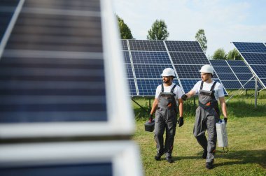 Güneş panelleri enerji çiftliğinde çalışan mühendis. Güneş enerjisi istasyonunda çalışan iki teknisyen..