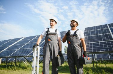 Güneş panelleri enerji çiftliğinde çalışan mühendis. Güneş enerjisi istasyonunda çalışan iki teknisyen..
