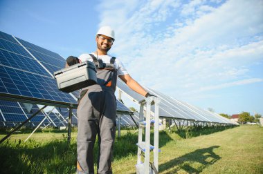 Güneş çiftliğinde üniformalı bir Hintli. Yetkin enerji mühendisi fotovoltaik hücrelerin çalışmalarını kontrol ediyor.