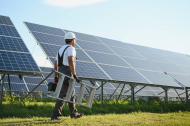 Üniformalı ve aletleri olan Hintli bir işçi güneş paneli çiftliğinde çalışıyor..