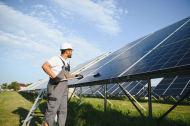 Profesyonel Hintli işçi güneş panellerini fırça ve yeşil elektrik teknolojisiyle temizliyor..