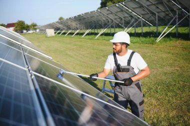 Genç bir Hintli temizlikçi güneş panellerini temizliyor..