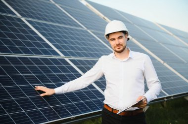 Young architect standing by solar panels.