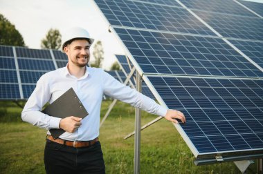 Young architect standing by solar panels.