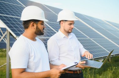 Güneş panellerinin arka planında iki mühendis ya da işadamı. Yenilenebilir enerji. Yeşil enerji.