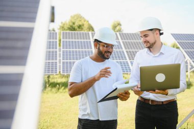 Güneş çiftliği, güneş paneli ve iki mühendis sistemin işleyişini kontrol etmek için yürür, dünyanın enerjisini korumak için alternatif enerji, temiz enerji üretimi için fotovoltaik modül fikri
