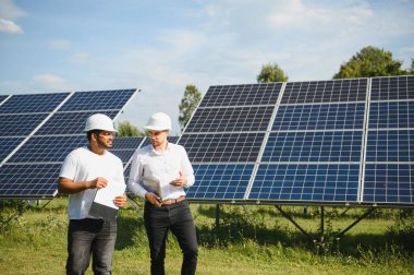 Güneş çiftliği, güneş paneli ve iki mühendis sistemin işleyişini kontrol etmek için yürür, dünyanın enerjisini korumak için alternatif enerji, temiz enerji üretimi için fotovoltaik modül fikri